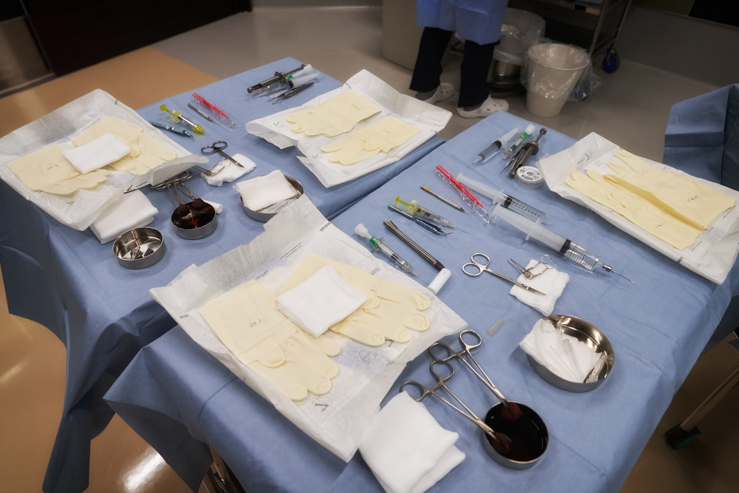 Chirurgische Instrumente und medizinische Hilfsmittel auf blauen Tüchern arrangiert.