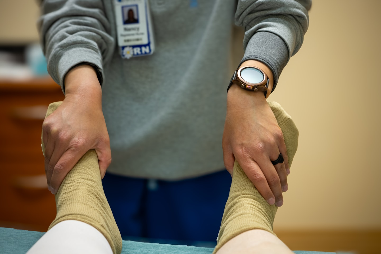 Medizinische Fachkraft untersucht den Fuß eines Patienten in einer Socke.